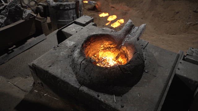 Worker putting a piece of metal into a furnace with a shovel