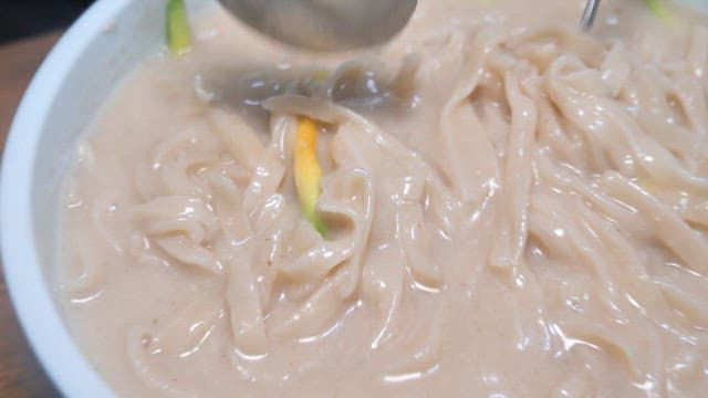 Spoonful of thick soup from the savory noodle in cold soybean soup