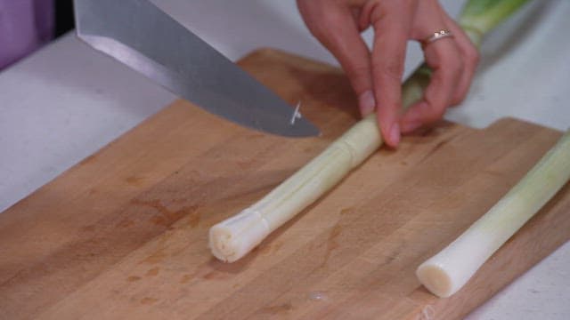 Cutting a green onion on a wooden board