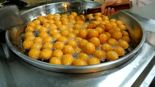 Frying spherical golden doughnuts
