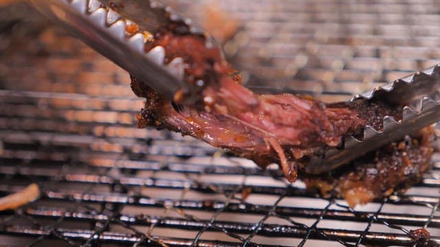 Grilled beef being held by tongs