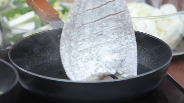 Placing the flounder in an oiled frying pan