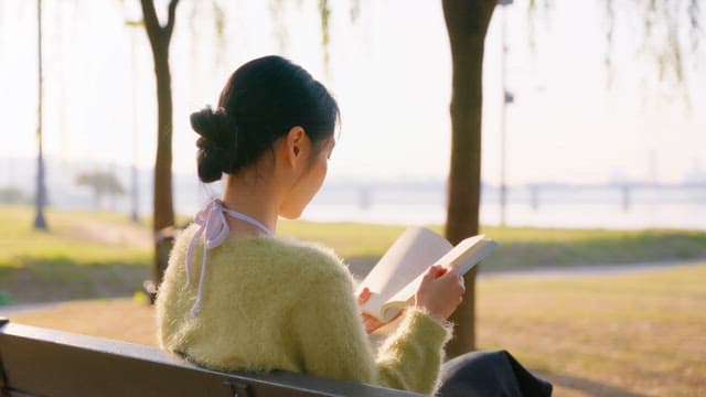 Woman reading a book on a park bench