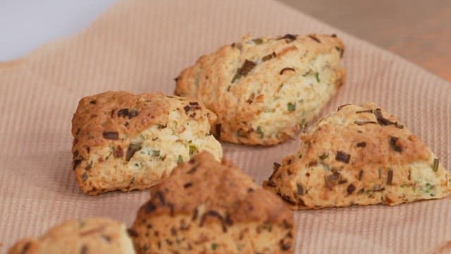 Freshly baked green onion scones on a brown kitchen towel