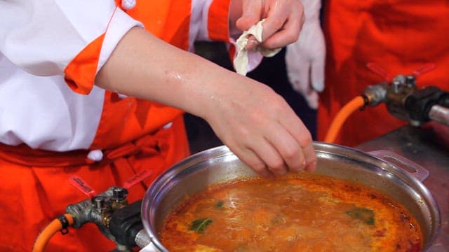 Chef putting hand-pulled dough in a pot