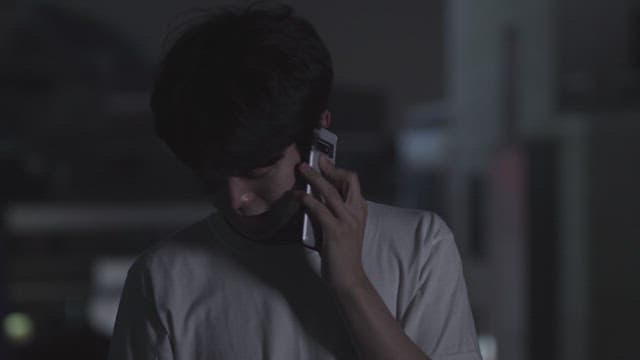Young man talking on the phone at night, looking concerned