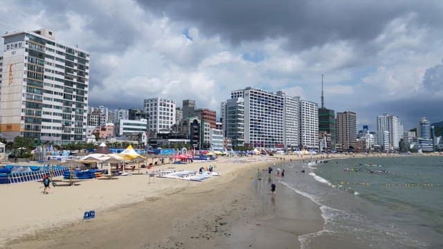 Summer vacationers enjoying the beach in a coastal city with many buildings