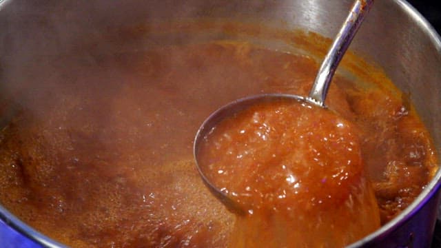Boiling spicy stew stirred with a ladle
