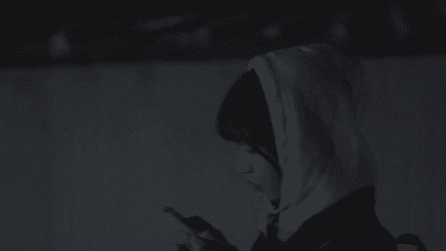 Girl walking alone with cell phone on a dimly lit street at night