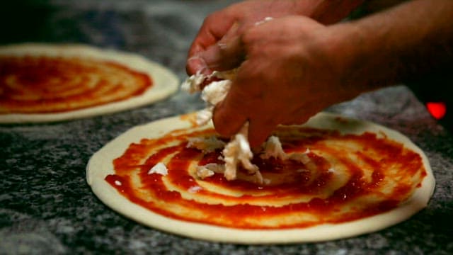Preparing a pizza with red tomato sauce and cheese topping