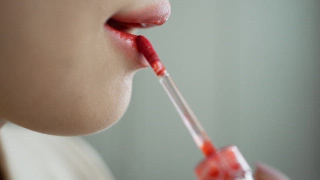 Applying red tint to lips with applicator