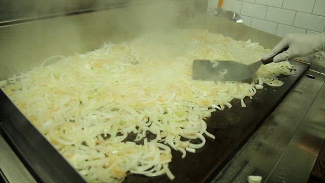 Onions being sautéed on a hot griddle
