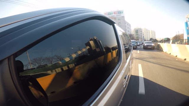 Afternoon traffic on a city road with cars reflecting on a vehicle's back mirror