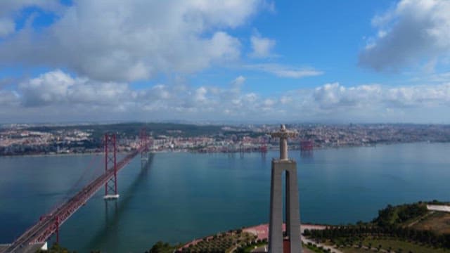View of a large statue and suspension bridge over the river on a clear day