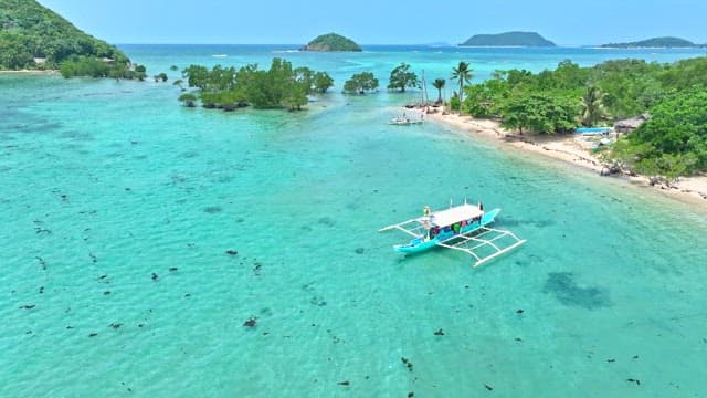 Bangka boat sailing near lush green tropical islands