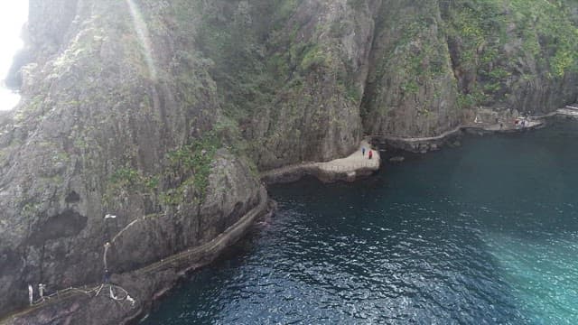Waves Sparkling in the Sunlight and a Rocky Cliff Walkway