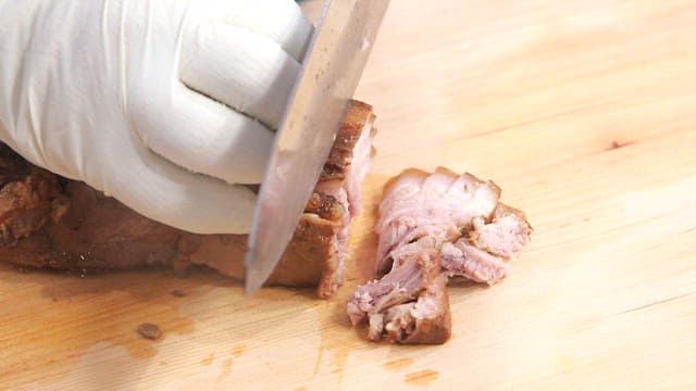 Slicing boiled pork slices on a wooden cutting board
