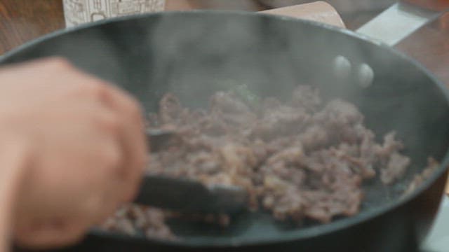 Cooking beef bulgogi in a pan with tongs
