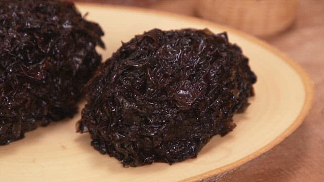 Two bunches of green seaweed on a wooden plate