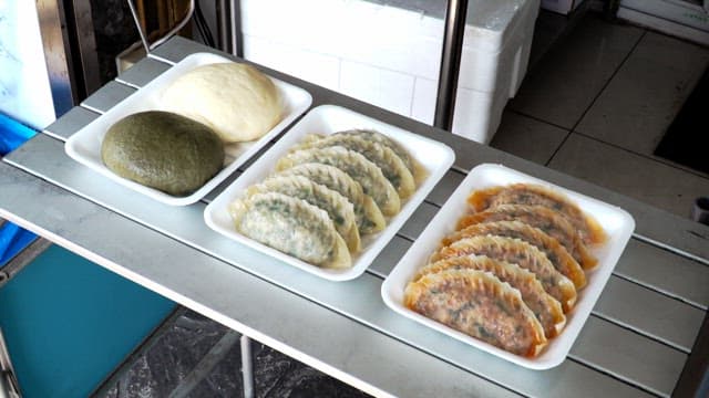 Kimchi dumplings, meat dumplings, and steamed buns prepared on the table in the store