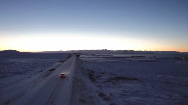 Car driving on a snowy road at dawn