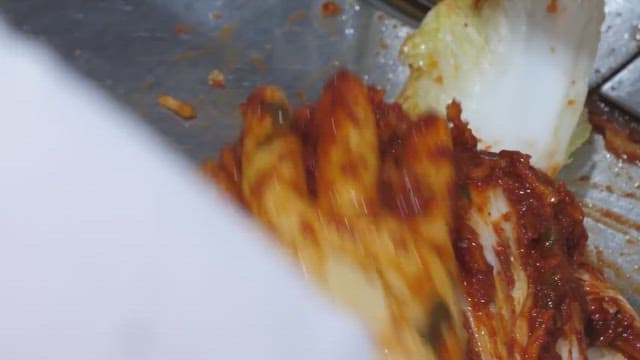 Making kimchi by adding chili pepper seasoning to cabbage