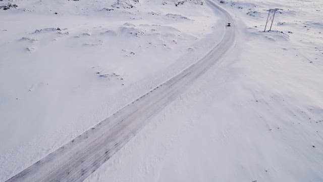 Snowy road winding through a vast landscape