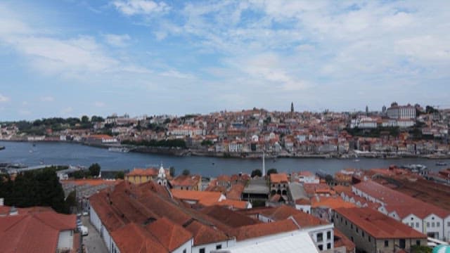 Panoramic View of a Riverside City with Red-Tiled Rooftops and Buildings