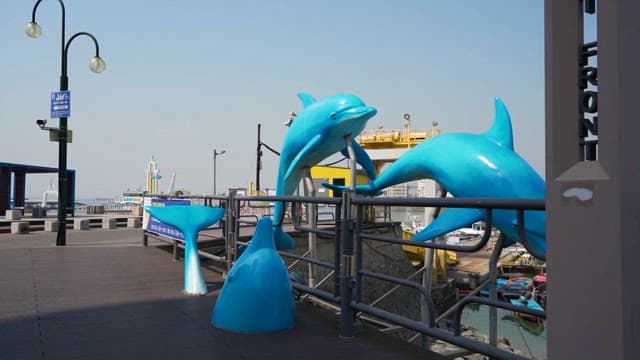 Dolphin sculptures at a sunny seaside pier