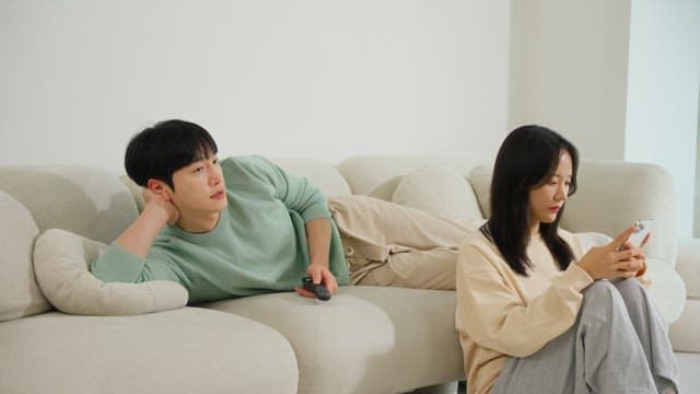 Using a smartphone and a man watching television on a sofa