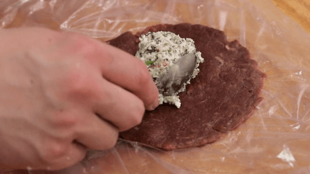 Stuffing mixture of dumpling being placed on raw beef meat