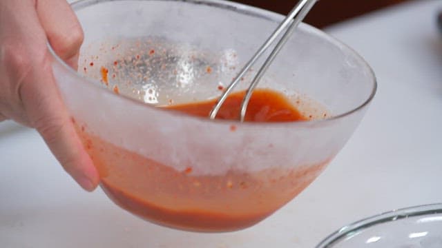 Pouring Spicy Sauce into a Glass Bowl with Ice and Conches