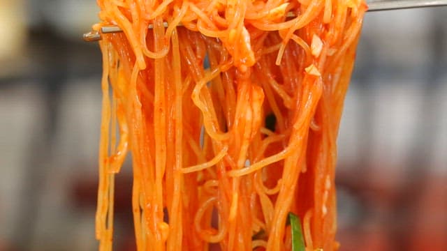 Chopstickful of delicious bibim jjolmyeon with fresh vegetables