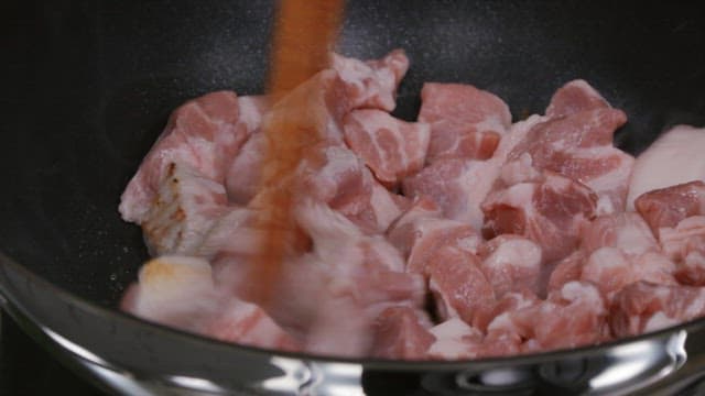 Frying pork with chopsticks in a hot frying pan