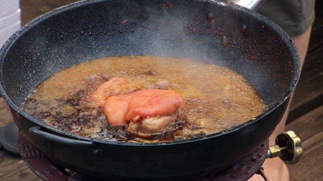 Pork being added to a pot with simmering soy sauce