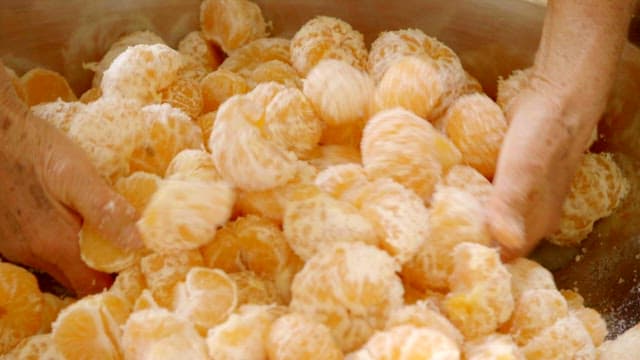 Peeled tangerines, sugar and nuts mixed in a large bowl