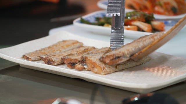 Grilled hairtail on a plate with side dishes