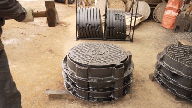 Worker handling manhole covers in a factory