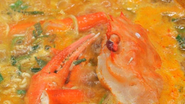 Appetizing seafood ramen with red crab boiling in a pot