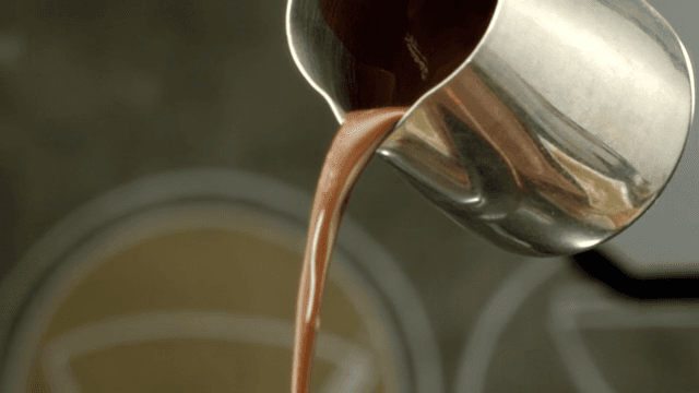 Chocolate syrup poured from a metal pot