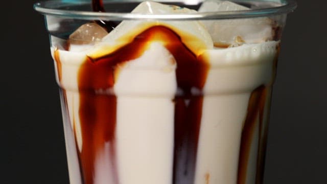 Glass filled with milk and chocolate syrup being poured