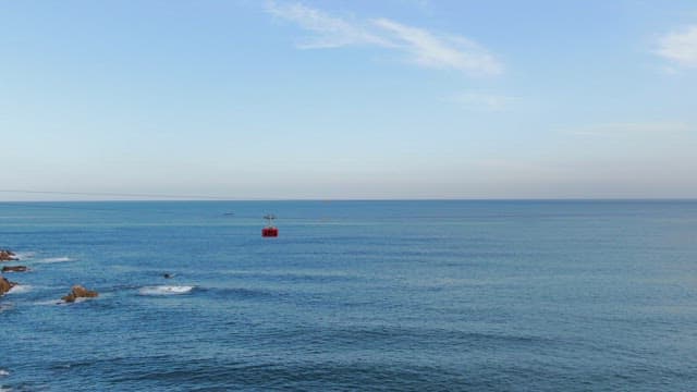 Cable car over the ocean with rocky coast