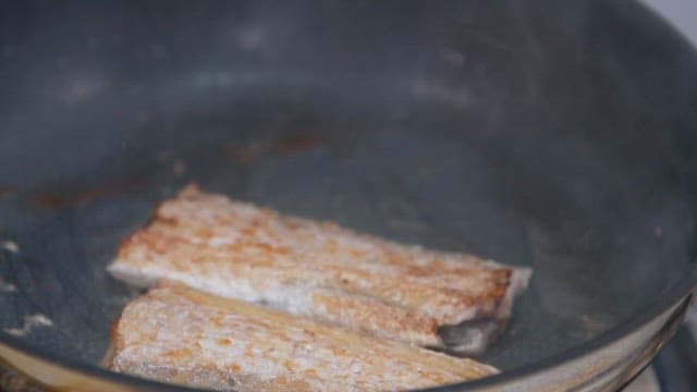 Golden brown hairtail fried in oil in a frying pan
