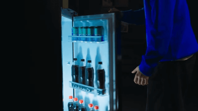 Person Choosing Beverage from Fridge at Night