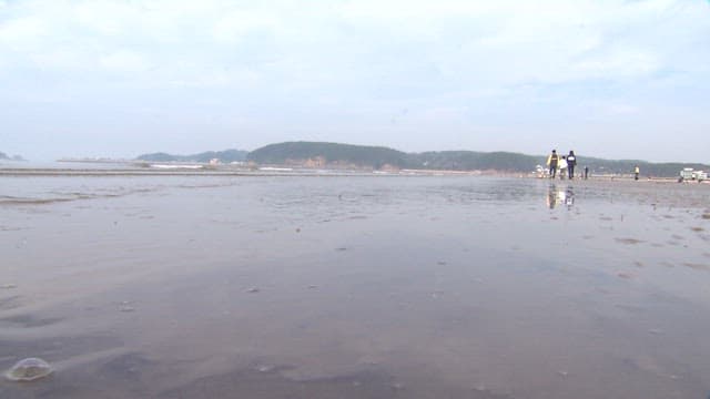 People enjoying tidal flats where the sea water rushes in