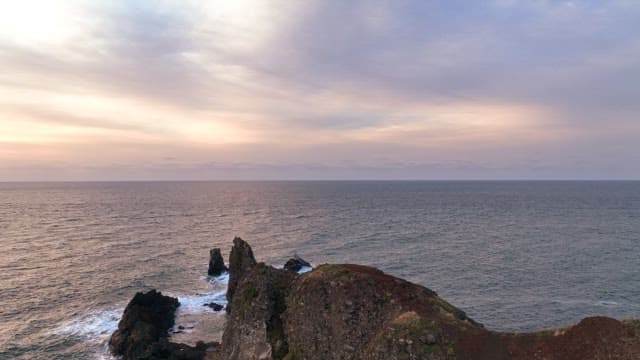 Coastal cliffs and a lighthouse at sunset
