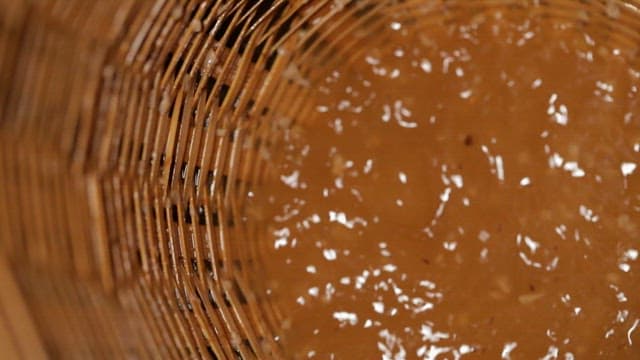Traditional Korean liquor made from lotus leaves being strained through a wooden strainer