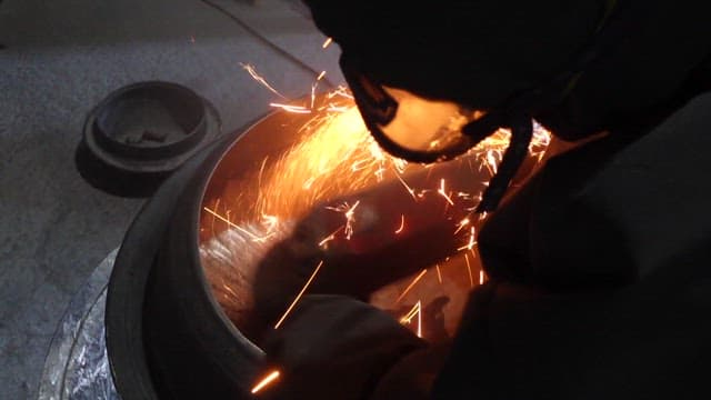 Worker welding and grinding a metal in an industrial workshop