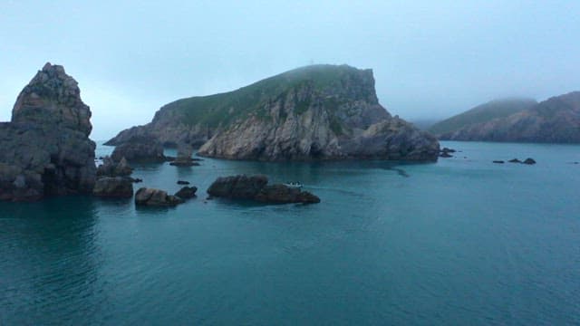Calm Ocean Scene with Rugged Cliffs and Boating