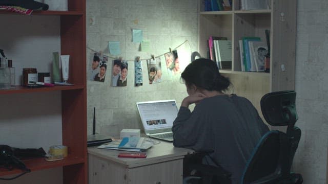 Woman suffering while looking at a laptop at a desk in her room